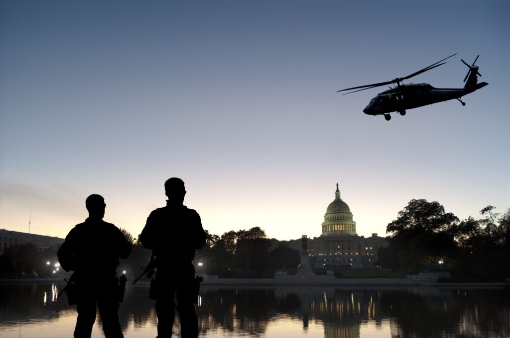 Silhouetted soldiers and helicopter in front of U.S. Capitol at dusk