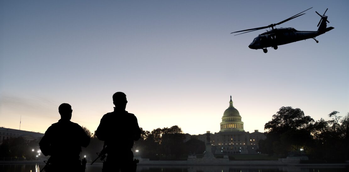 Silhouetted soldiers and helicopter in front of U.S. Capitol at dusk